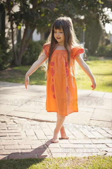 Caucasian girl playing barefoot in backyard