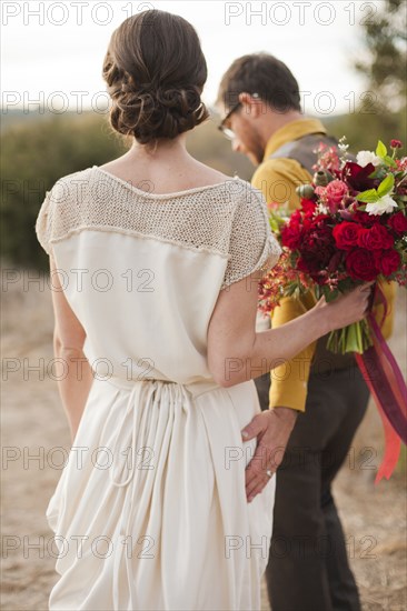 Bride and groom walking on rural hilltop