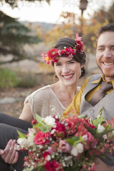 Bride carrying groom and bouquet in rural field