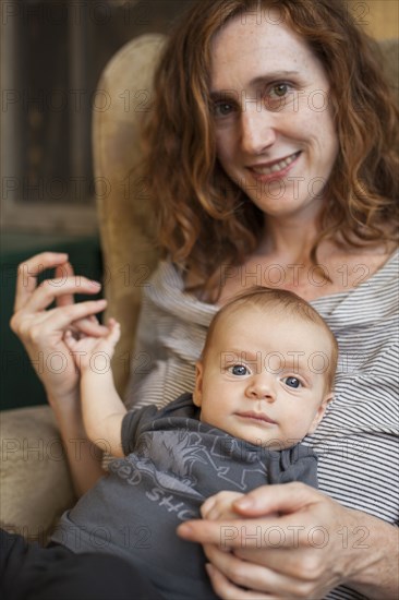 Smiling mother holding baby in armchair