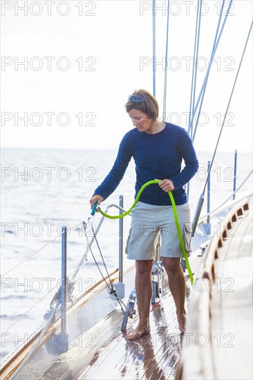 Caucasian woman washing sailboat deck