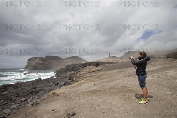 Caucasian woman photographing rocky beach