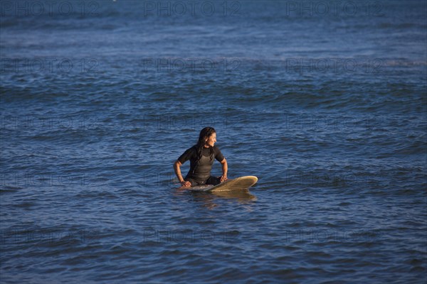 Hispanic surfer floating on surfboard in ocean