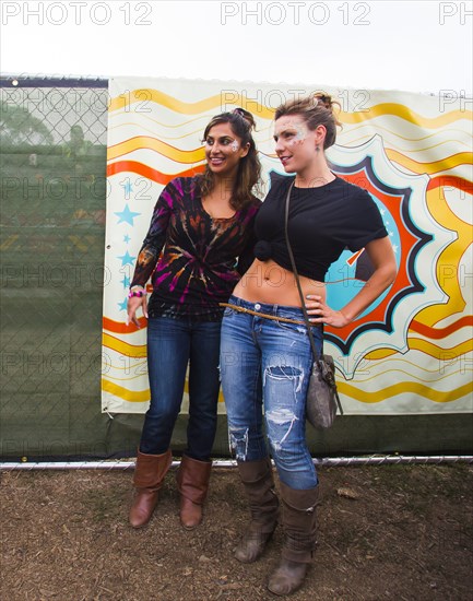 Women smiling near multicolor mural