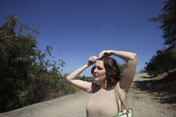 Caucasian woman pinning her hair on dirt path