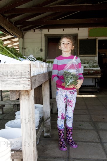 Mixed race girl holding bag of produce in farmers market