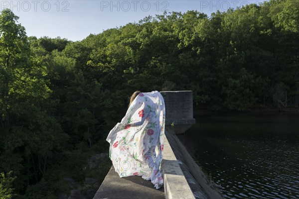 Woman playing with fabric on stone bridge