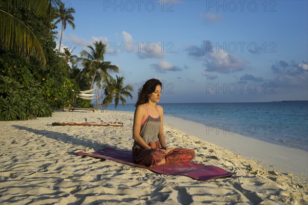 Caucasian woman meditating on tropical beach