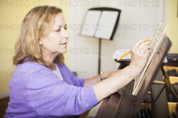 Caucasian musician writing sheet music at piano
