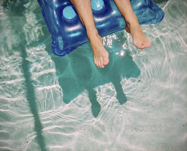 Feet of Caucasian woman floating on raft in swimming pool