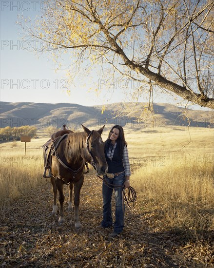 Woman leading horse on dirt path