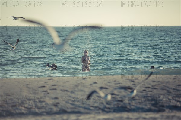 Seagulls flying near Caucasian teenage girl standing in ocean