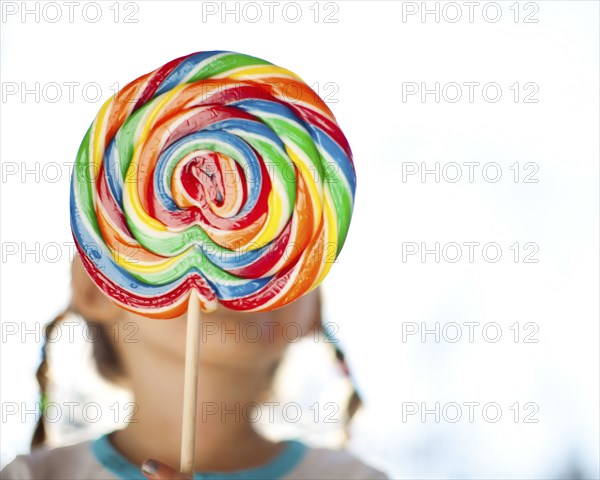 Girl holding lollipop in front of face