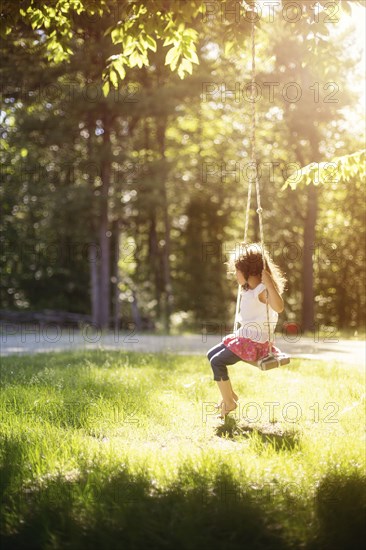 Girl sitting on swing in field