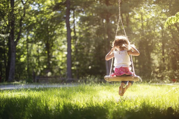 Girl sitting on swing in field