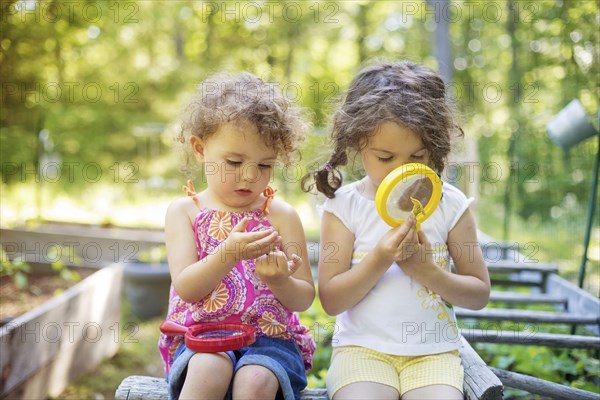 Girls examining garden plants with magnifying glass