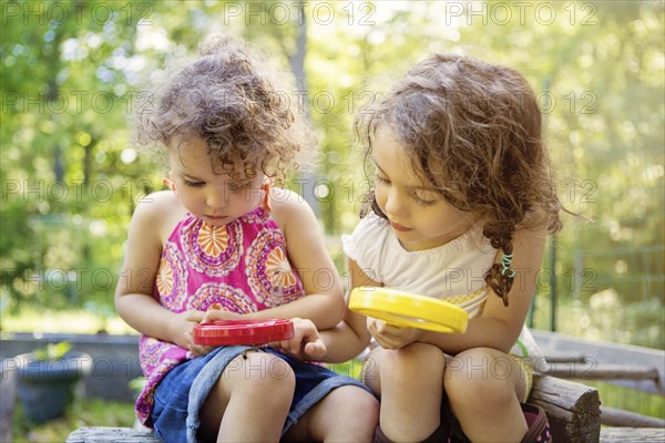 Girls examining caterpillar with magnifying glass