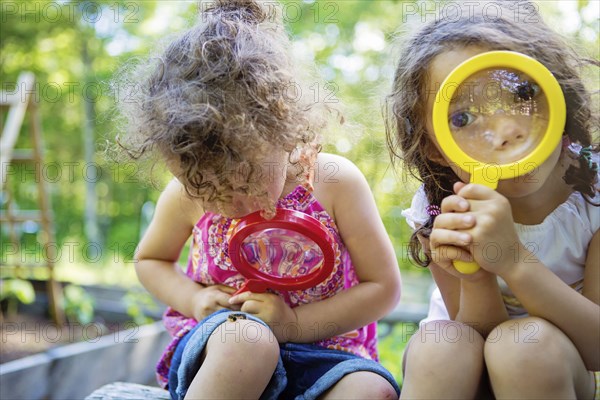 Girls examining caterpillar with magnifying glass