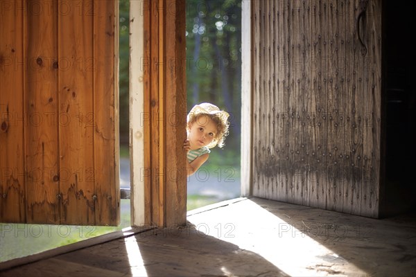 Curious girl peering around open door