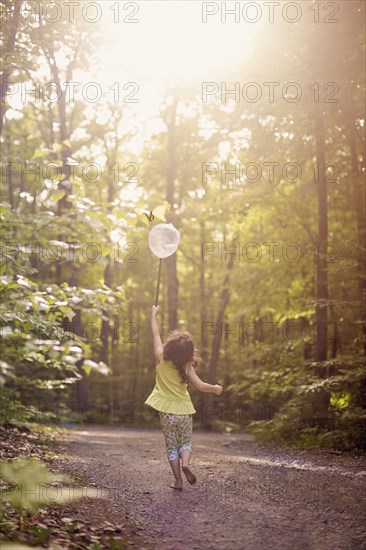 Girl playing with butterfly net in forest