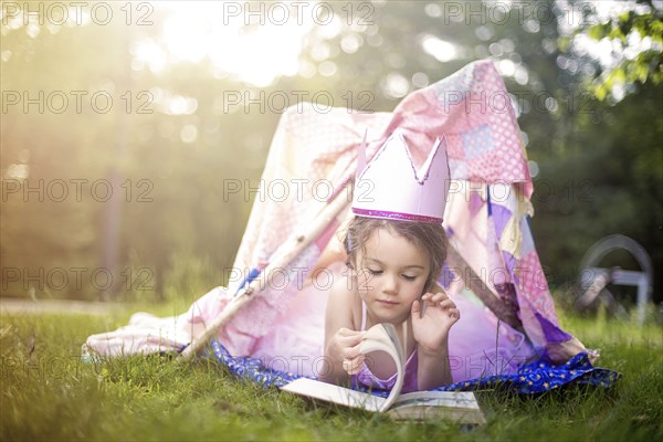 Girl reading in tent in backyard