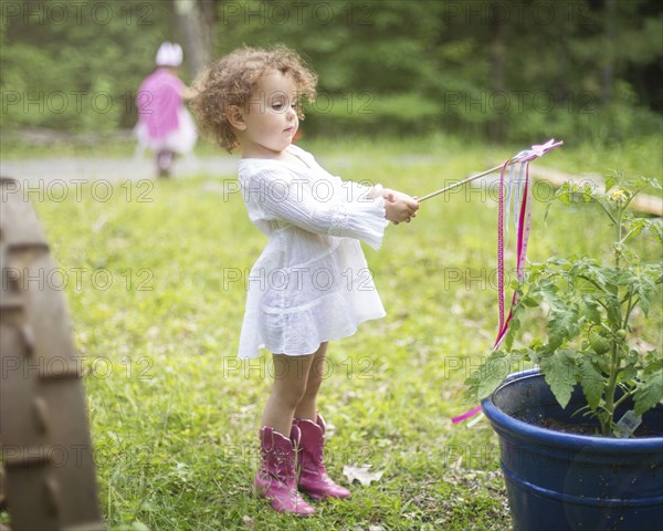 Girl playing with wand in backyard garden