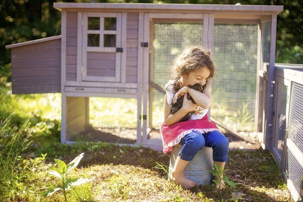 Girl hugging chicken in farm yard