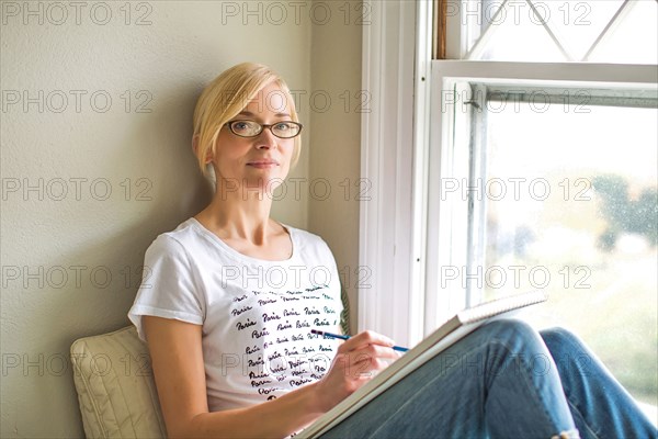 Caucasian woman drawing in windowsill