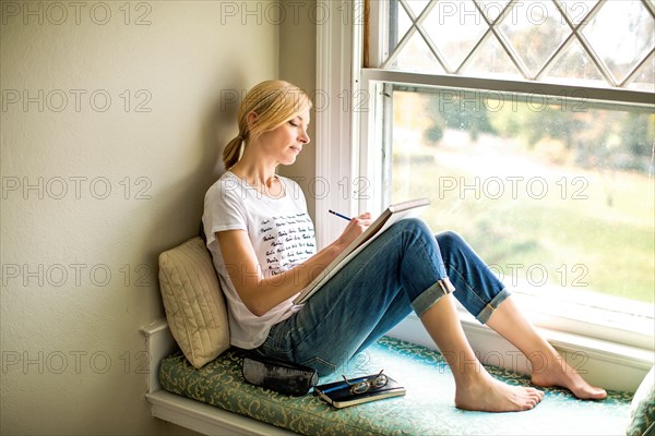 Caucasian woman drawing in windowsill