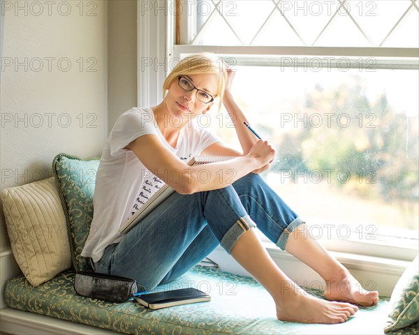 Caucasian woman sitting in windowsill