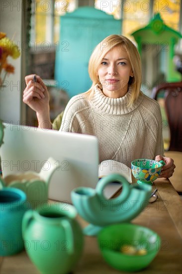 Caucasian entrepreneur using laptop in shop