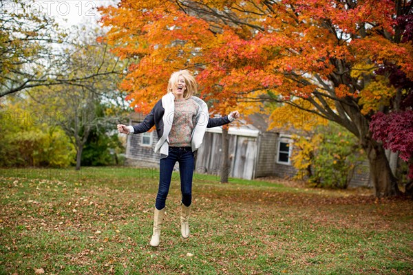 Caucasian woman jumping for joy in backyard