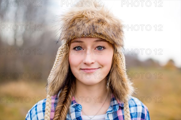 Caucasian teenage girl wearing fur hat in field