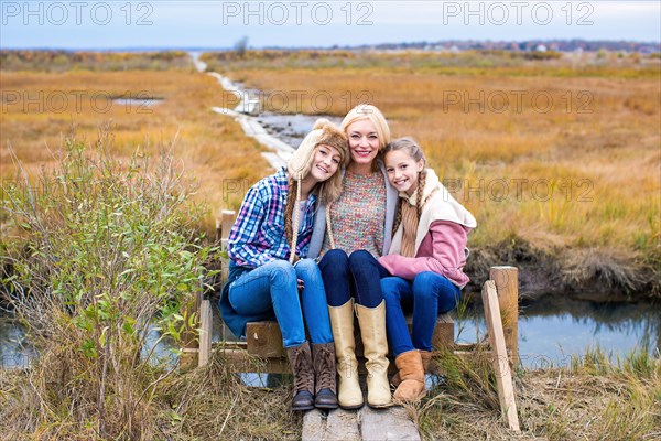 Mother and daughters hugging on walkway in rural field