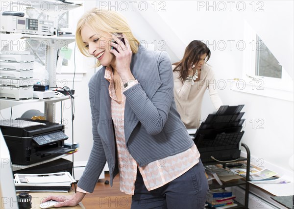 Caucasian businesswomen talking on cell phone in office