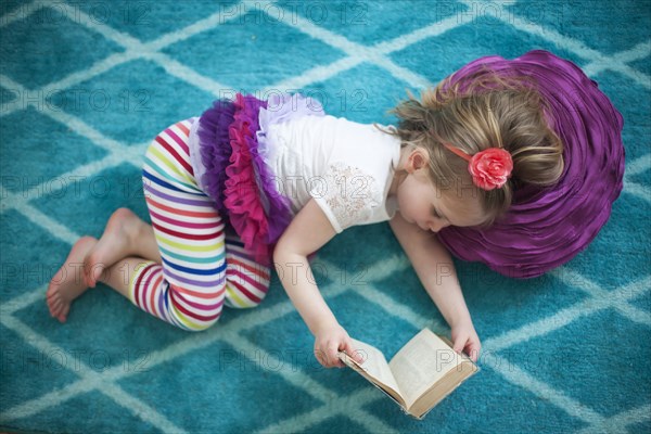 Girl reading book on floor