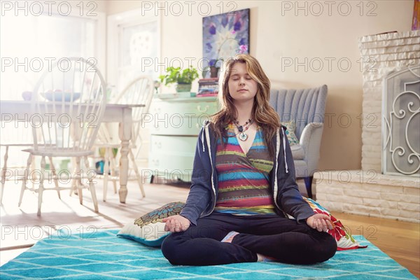 Caucasian woman meditating in living room