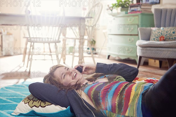 Caucasian woman talking on cell phone on floor