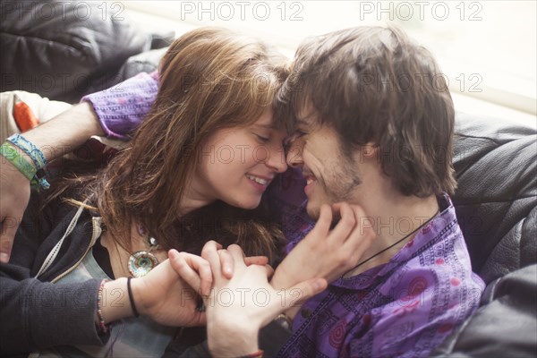 Caucasian couple holding hands on sofa