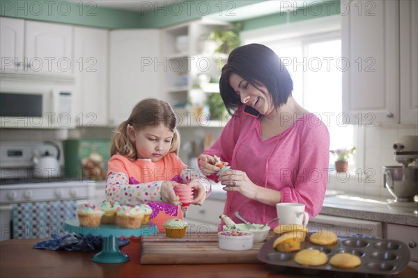 Caucasian mother and daughter baking in kitchen