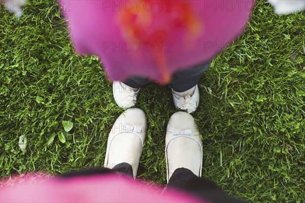 High angle view of feet of mother and daughter in grass