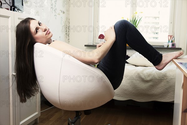 Caucasian teenage girl sitting in armchair