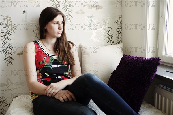 Caucasian teenage girl sitting on bed