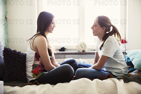 Smiling sisters talking on bed