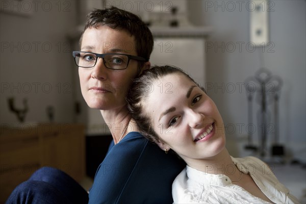 Caucasian mother and daughter sitting back to back