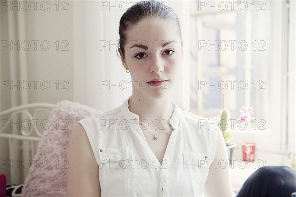 Caucasian teenage girl sitting on bed