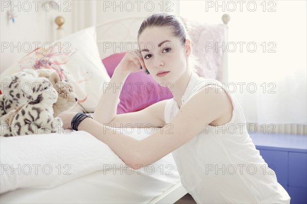 Caucasian teenage girl leaning on bed