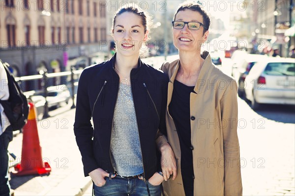 Caucasian mother and daughter walking on city sidewalk