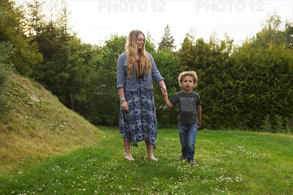 Mother holding hand of son in rural field