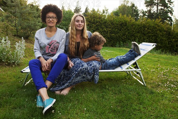 Teenagers and boy relaxing on lawn chair